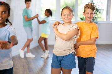 Positive tweenagers, boy and girl dancing together slow ballroom dances in pair during group children choreography lesson ..