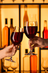 Hands of women clinking glasses of red wine in bar