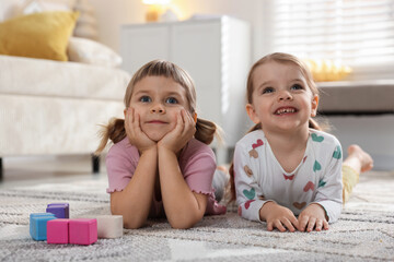 Fototapeta premium Cute little sisters lying on floor at home