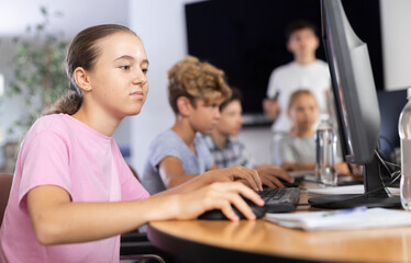 Portrait of female schoolgirl at computers in shool computer class