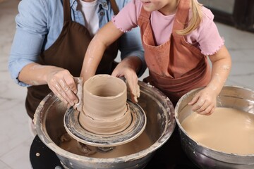 Hobby and craft. Mother with her daughter making pottery indoors, closeup