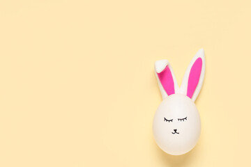 Easter eggs with drawn face and bunny ears on beige background