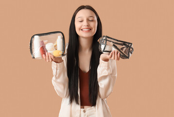 Teenage girl with transparent cosmetic bags on beige background