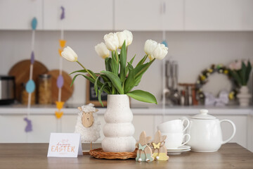 Vase with tulips, Easter decor and tea set on table in kitchen