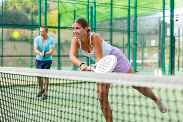 Woman padel tennis player training on court. Woman using racket to hit ball.