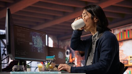 CTO manager in AI startup drinking coffee while coding applications in programming languages. Chief technician officer enjoying hot beverage while doing code testing and quality assurance, camera B