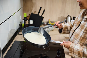 Woman Cooking Crepe Batter on Stove in a Modern Home Kitchen