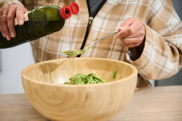 Close-Up of Salad Preparation with Olive Oil in a Wooden Bowl