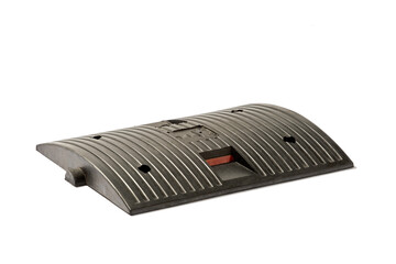 Detailed Image of a Black Rubber Speed Bump Used for Traffic Regulation, Featuring Grooved Surface...