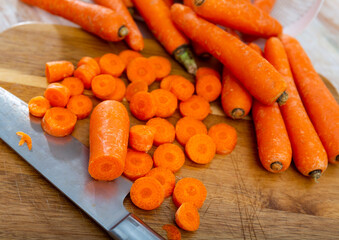 Pile of fresh sweet carrots on wooden cutting board. Preparing food concept.