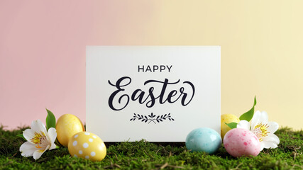 Minimalist Happy Easter greeting card with pastel painted colorful eggs and white flowers on green moss against studio yellow pink gradient background.