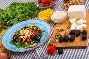 Image of ready-made salad and its ingredients on the table indoors.