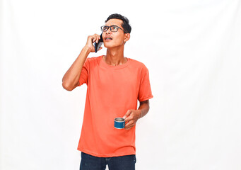Young adult in casual wear engrossed in phone conversation, with beverage