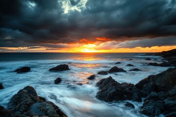 Obraz premium Dramatic sunset over coastal rocks with stormy clouds