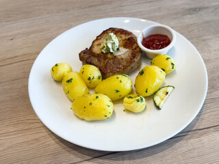 Grilled pork chop with herb butter and potatoes on plate
