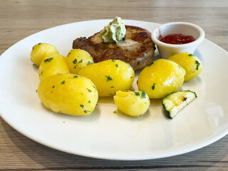 Delicious steak with herb butter, boiled potatoes, and zucchini garnished with parsley