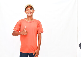 Smiling Young Man In Casual Attire Giving Thumbs Up Against Plain Background