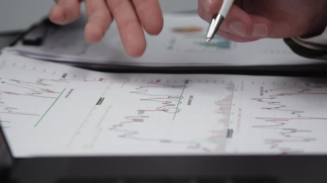 Two businessmen brainstorming with charts, papers, and a computer. Concept effective teamwork, strategy planning, and small business startup growth in an office environment.