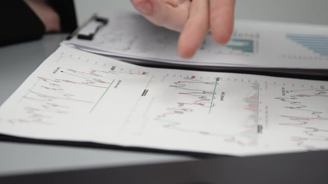 Two businessmen brainstorming with charts, papers, and a computer. Concept effective teamwork, strategy planning, and small business startup growth in an office environment.