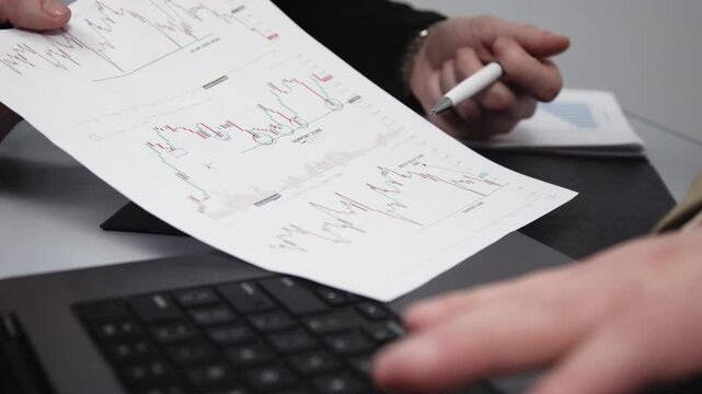 Two businessmen brainstorming with charts, papers, and a computer. Concept effective teamwork, strategy planning, and small business startup growth in an office environment.