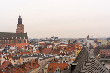 Obraz premium Scenic aerial view of European city with historic architecture, red rooftops, and church tower on an overcast day. Concept of urban landscape, heritage, and old town charm.