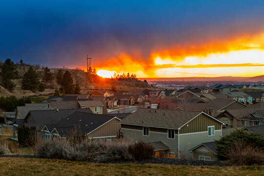 Rain falls from dark storm clouds over a golden hour sunset above downtown Spokane, Washington USA, seen from a hilltop neighborhood in Liberty Lake, Washington.