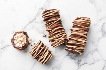 Delicious chocolate puffed rice bars on white marble table, flat lay