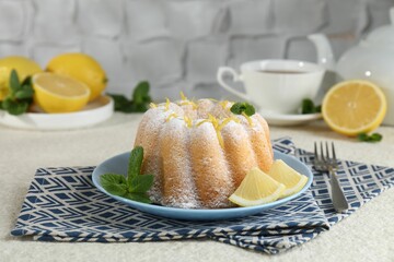 Delicious cake with lemon zest, powdered sugar and mint on light textured table, closeup