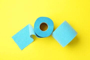 Light blue toilet paper roll on yellow background, top view