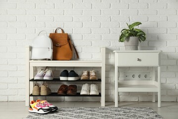 Shoe storage bench with different footwear and houseplant indoors