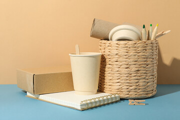 Handmade basket, notepad, box and paper cup on beige background
