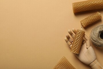 Homemade candles, wooden hand and twine on beige background, space for text