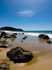 Sandy beach with scattered rocks on a sunny day