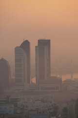 Aerial view of Abu Dhabi in the morning light, as the rising sun casts a golden glow over the city's modern skyline.