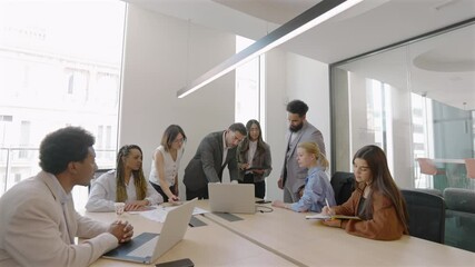 A varied and diverse group of skilled business professionals gathers together in a spacious conference room, actively collaborating on analyzing financial data and discussing intricate sales reports - Powered by Adobe