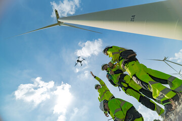 engineers conducting an aerial inspection of a wind turbine using a drone. The scene highlights...
