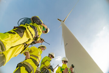 A team of engineers celebrates success after completing wind turbine maintenance at a wind farm....