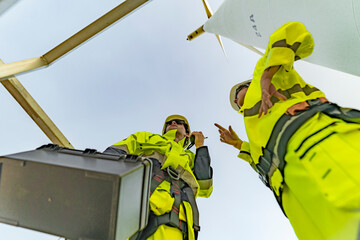 A team of engineers celebrates success after completing wind turbine maintenance at a wind farm....