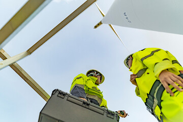 A team of engineers celebrates success after completing wind turbine maintenance at a wind farm....