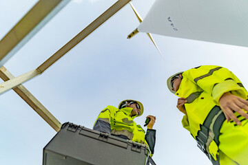 A team of engineers celebrates success after completing wind turbine maintenance at a wind farm....
