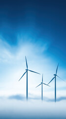 Fototapeta premium Three wind turbines rise above a sea of fog under a bright blue sky, symbolizing renewable energy and environmental sustainability.