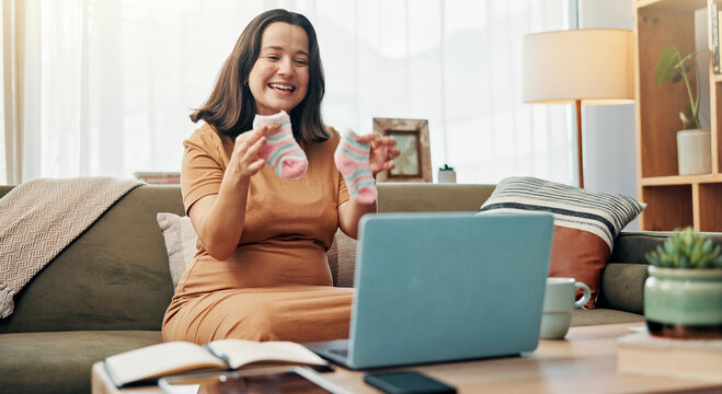 Pregnant, woman and baby clothes for video call, smile and sharing motherhood on social media with laptop. House, influencer and socks for gender reveal on app, communication or preparation for child