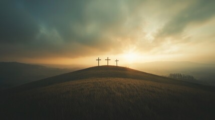 Obraz premium Wide panoramic view of three crosses on a hill with wind-blown grass at dawn.