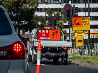 a work truck carrying traffic barriers at a construction zone on an urban street featuring warning...