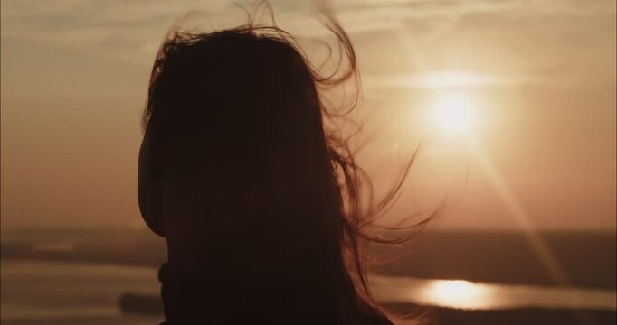 Woman enjoying freedom with hair blowing in wind at sunset