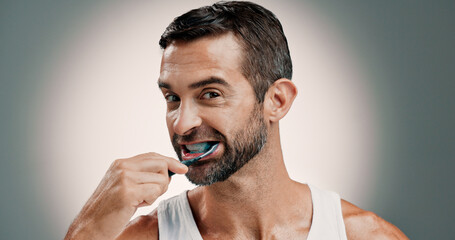 Oral hygiene, portrait and man brushing teeth on studio background for fresh breath, grooming or...