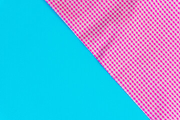 A dual-textured background featuring a vibrant pink gingham fabric against a clean, solid turquoise surface.