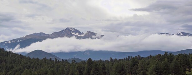 Obraz premium Storm clouds rolling in over the snow-capped mountains in Rocky Mountain National Park. 