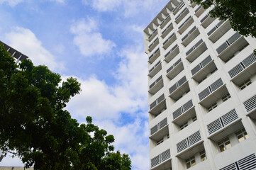 Obraz premium A modern high-rise building with clean architectural lines and open balconies, set against a bright sky. The urban design blends functionality and style, making it ideal for residential or commercial 