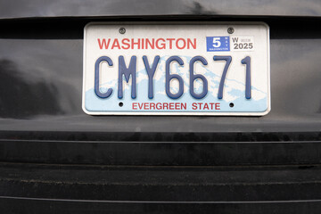 Washington car license plate with tab 2025 on the black car. DMV sticker close up for year 2025 on a license plate